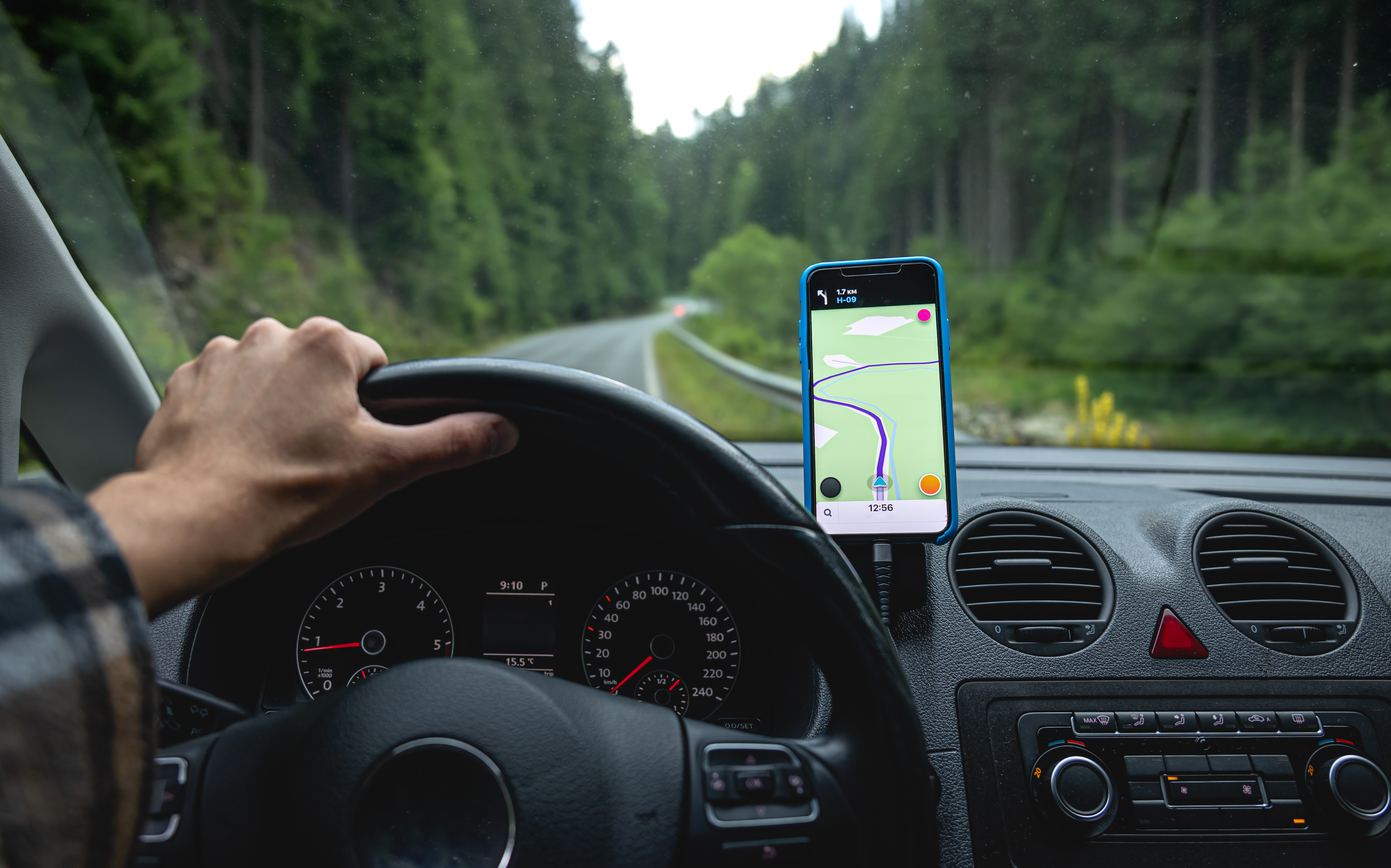 A man is driving on a gps navigator in a mountainous area, a view from inside the car.